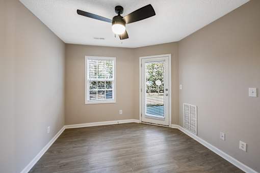A room with a ceiling fan and a door leading to a balcony.