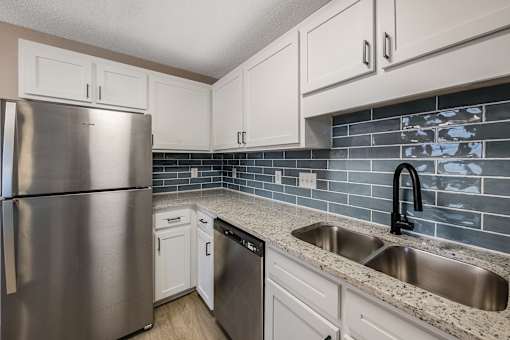 A kitchen with a stainless steel refrigerator and a sink.