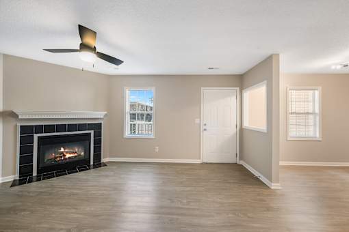 A living room with a fireplace and a ceiling fan.