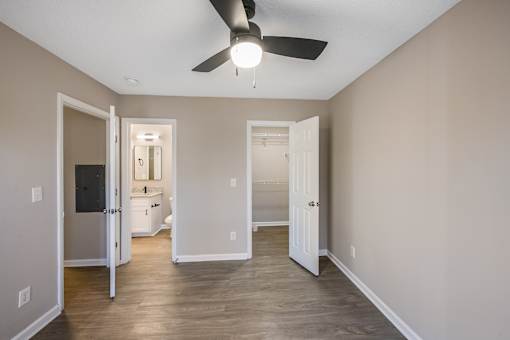 A room with a ceiling fan and a doorway leading to a bathroom.