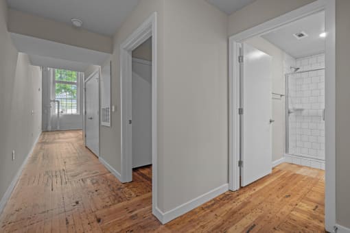 a renovated bedroom and hallway with wood floors and white walls at Spinning Mill Lofts, Clayton, NC 27520