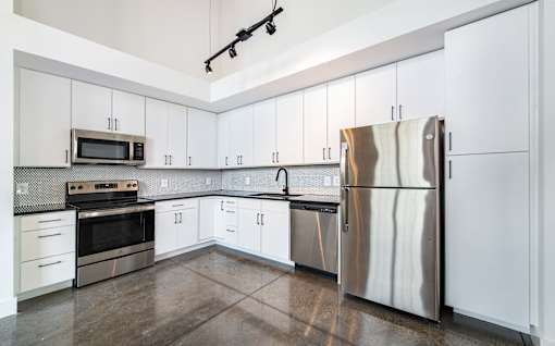 A kitchen with white cabinets and a stainless steel refrigerator at Judson Mill Lofts, South Carolina