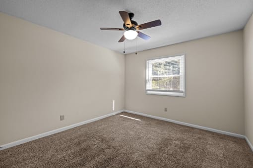 an empty room with a ceiling fan and a window