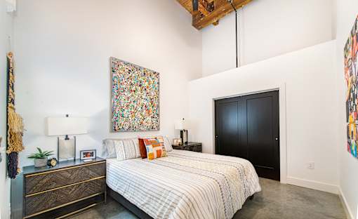 A bedroom with a large bed and a painting on the wall at Judson Mill Lofts, Greenville, SC 296110