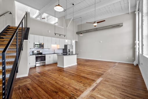 an open living room with a kitchen and a staircase at Spinning Mill Lofts, Clayton, NC 27520