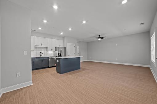 A spacious room with a kitchen area and wooden flooring.at Regency Townes, Winterville North Carolina  
