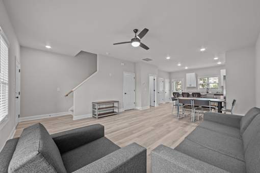 A living room with grey couches and a ceiling fan.