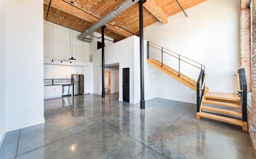 A large open space with a staircase and a kitchen area at Judson Mill Lofts, Greenville