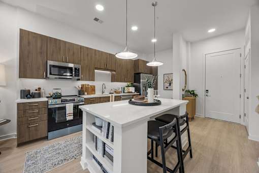 A modern kitchen with a white island and wooden cabinets.at Adler Montford Park + Drexel Townes, Charlotte, NC, 28209