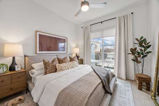A bedroom with a large bed, a ceiling fan, and a window with curtains.at Adler Montford Park + Drexel Townes, Charlotte, NC, 28209