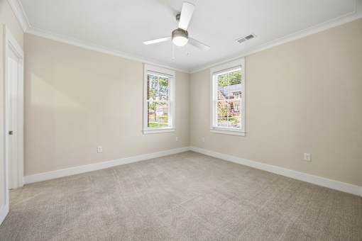 A room with a ceiling fan and two windows.