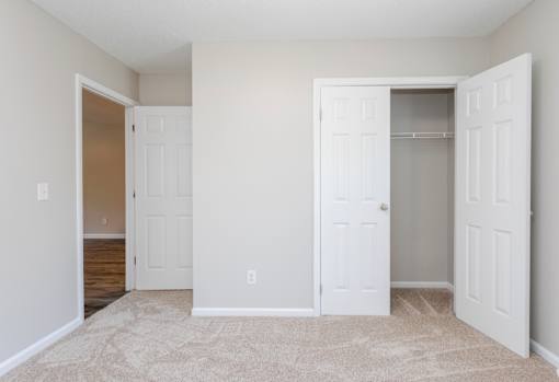 A white door is open to a room with a carpeted floor.