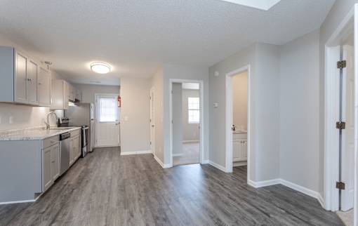 A kitchen with white cabinets and a grey floor.