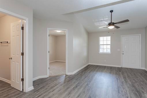 A room with a ceiling fan and wood flooring.