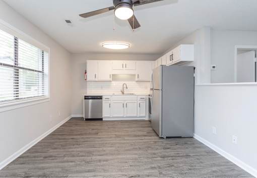 A kitchen with white cabinets and a grey fridge.