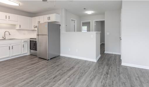 A kitchen with a refrigerator, sink, and cabinets.