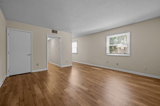 the living room and dining room of an empty house with wood flooring