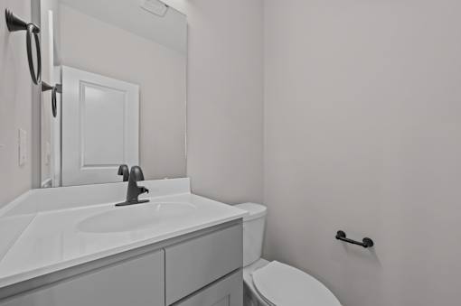 A bathroom with a toilet, sink, and mirror.