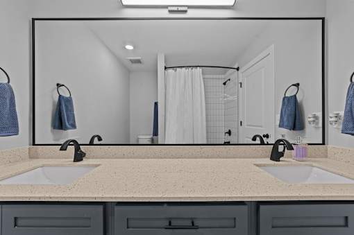 A bathroom with a large mirror above a double sink.at Regency Townes, Winterville  