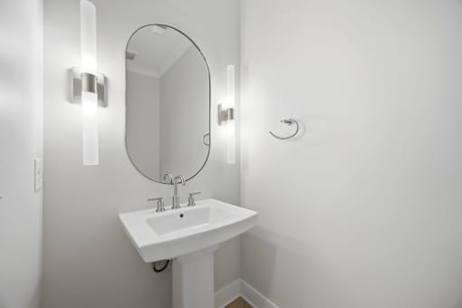 A white sink with a round mirror above it.