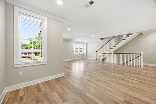 A spacious room with wooden floors and a staircase.