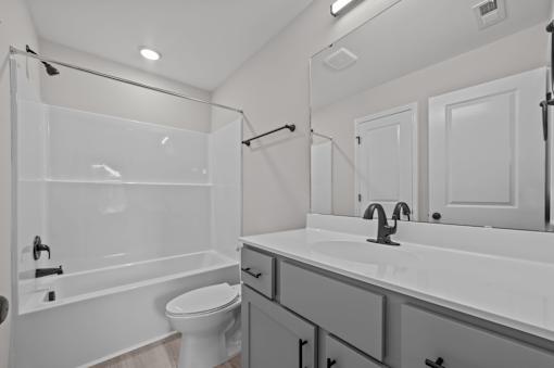 A white bathroom with a toilet, sink, and shower.