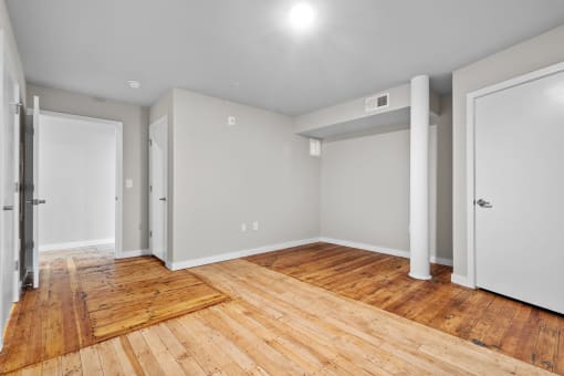 an empty living room with wood flooring and white walls at Spinning Mill Lofts, Clayton, NC 27520