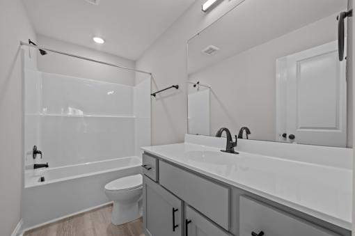 A white bathroom with a toilet, sink, and shower.