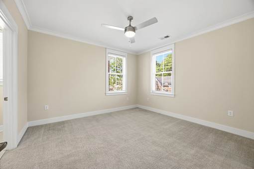 A room with a ceiling fan and two windows.