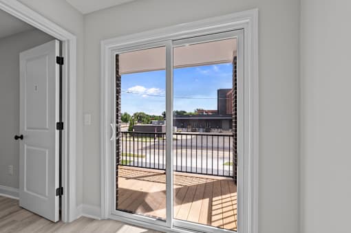 A white door with a black handle is open to a balcony with a black railing.