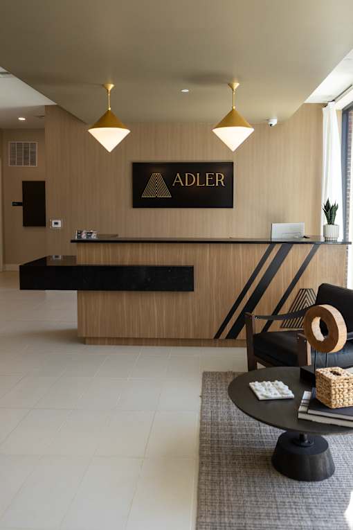 A reception area with a black and gold reception desk and a sign that says "ADLER".