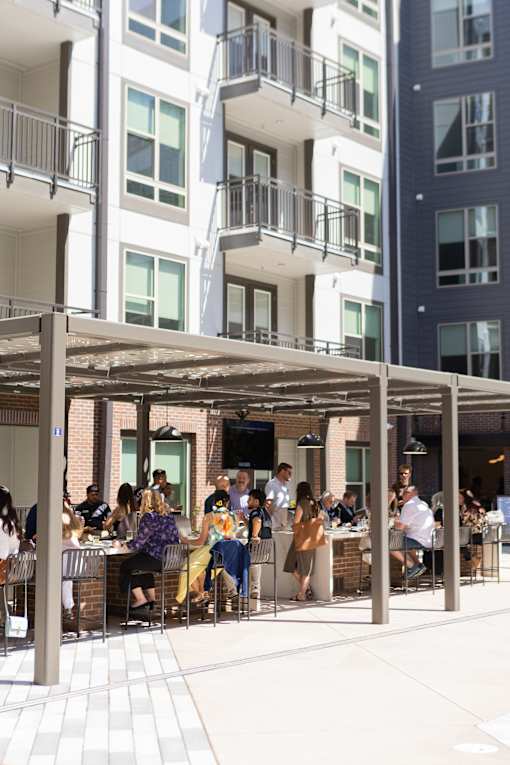 People are sitting at tables under a canopy outside a building.