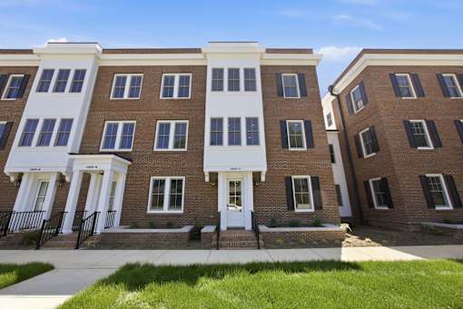 A row of brown and white townhouses with black railings.