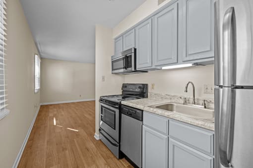 an empty kitchen with white cabinets and stainless steel appliances