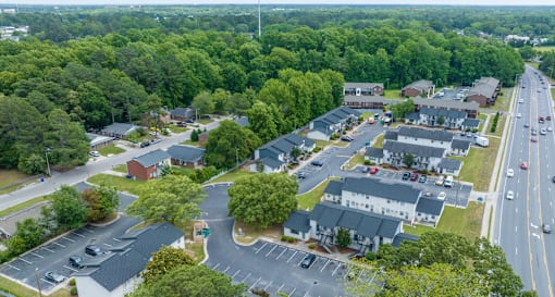 A road with cars and a parking lot with trees.