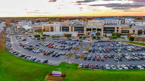 A parking lot with cars and a building in the background during sunset.