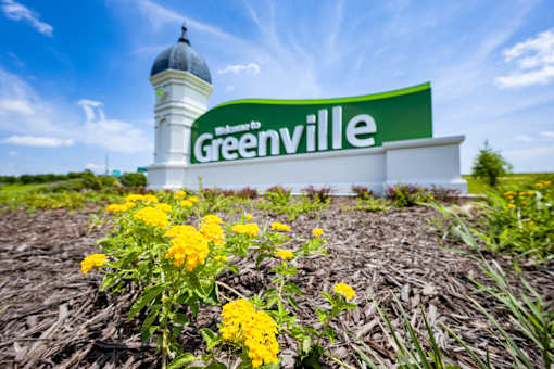 A sign that says Greenville in front of a white dome.