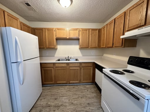 an empty kitchen with white appliances and wooden cabinets