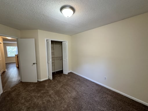 an empty living room with carpet and a door to a closet