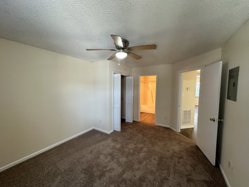 the living room of an empty home with a ceiling fan