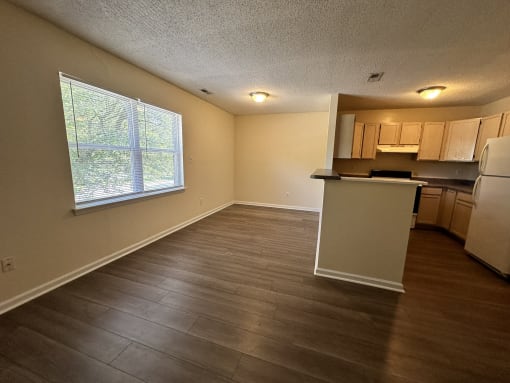 an empty living room and kitchen with a large window