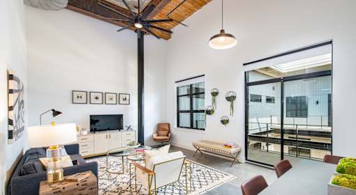 A living room with a dark blue sofa, a wooden coffee table, and a TV on the wall at Judson Mill Lofts, South Carolina 29611
