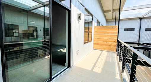 A glass door is open to a hallway with a wooden wall at Judson Mill Lofts, Greenville, SC 29611