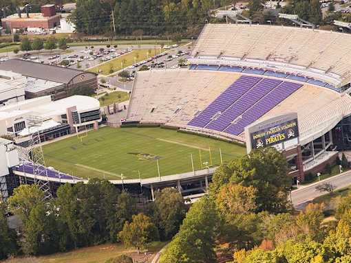 A stadium with a purple field and a yellow sign that says "Pirates".