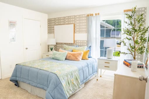 A bedroom with a bed, nightstand, and a window with curtains.