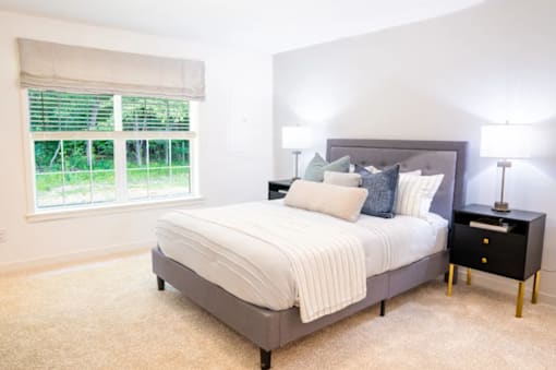 A bedroom with a large bed and a window with blinds.
