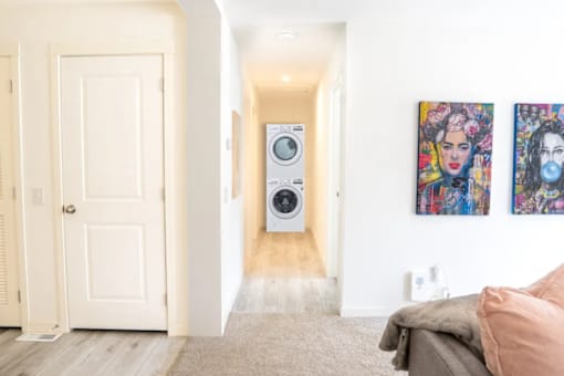 A hallway with a washing machine in the middle and two paintings on the wall.