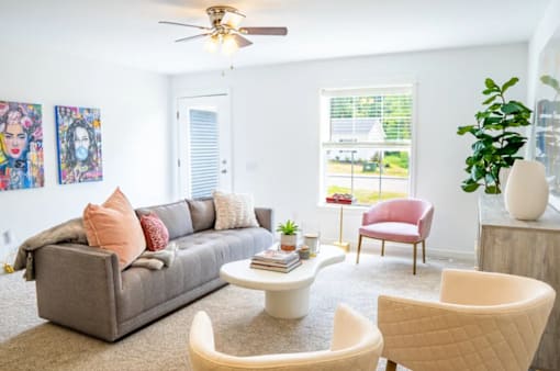 A living room with a grey couch, a red chair, a white coffee table, and a ceiling fan.