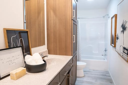 A bathroom with a white counter top and a black bowl with white cotton balls in it.
