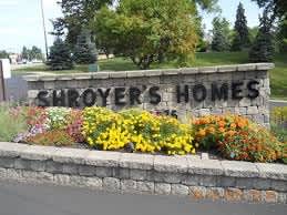 A neighborhood entrance reading with flowers and a sign reading "Shroyer's Homes".